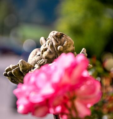 Dekoelfe mit einer pinken Blume im sommerlichen Garten